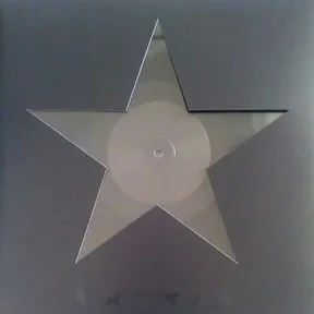 A large five-pointed star cut out of a translucent, faintly iridescent vinyl record — its circular label and center hole visible at the middle — set against a flat grey background.