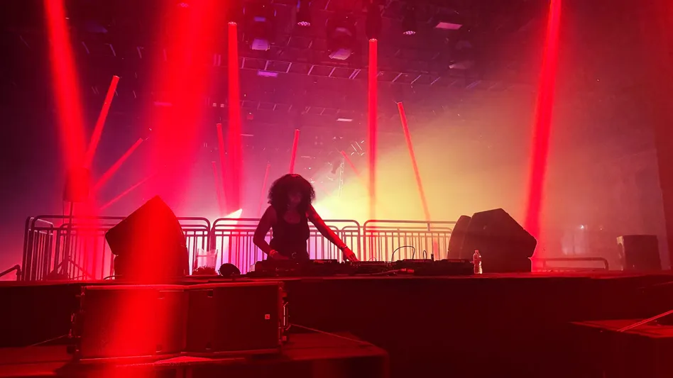 DJ Minx, a legendary artist out of Detroit spins house tracks while backlit by flood lights and lasers in front of a crowd