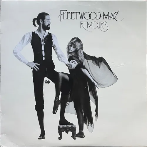 A black-and-white photograph on a plain light background shows a bearded man in a vest, puffy shirt and tights standing with one leg raised on a small ornate stool, beside a blonde woman in a flowing black shawl and dress, with stylized script text across the top.