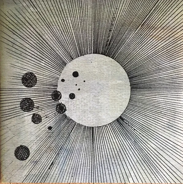 A black-and-white pen-and-ink drawing of a large pale circle radiating dense hand-drawn rays like a sun, with a scattering of small dark dots and speckled spheres trailing off to the lower left across a textured off-white background.