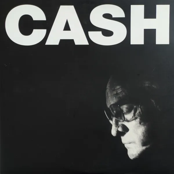 High-contrast black-and-white photo of an older man's face in profile wearing glasses, head bowed and emerging from deep shadow in the lower right, beneath large bold white capital letters across the top of a black background.
