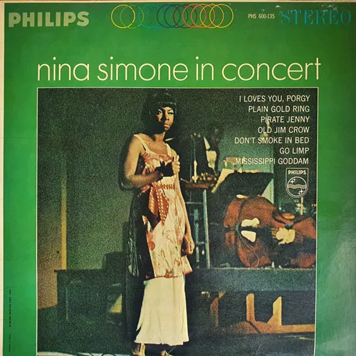 A green-bordered LP sleeve featuring a grainy stage photograph of a woman in a long pale patterned gown standing beside instruments in dim light, with a track list in cream type to the right.