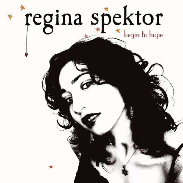 A high-contrast black-and-white photo of a curly-haired woman gazing over her shoulder against a white background, scattered with small orange stars and a tiny red heart dangling from a thin drawn line.