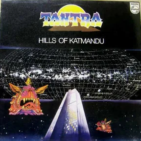 A cosmic starfield with a glowing grid-mapped galaxy sphere and a rising sun arcs above a futuristic silver spire, flanked by ornate, fanged Himalayan-style demon masks in orange, pink and gold, set against a deep black and blue night sky.