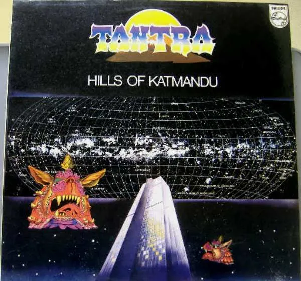A cosmic starfield with a glowing grid-mapped galaxy sphere and a rising sun arcs above a futuristic silver spire, flanked by ornate, fanged Himalayan-style demon masks in orange, pink and gold, set against a deep black and blue night sky.