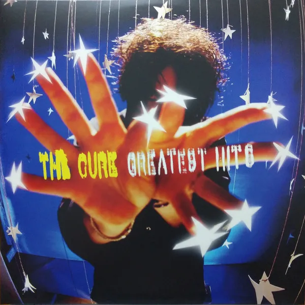 A person with wild dark curly hair holds both hands outstretched toward the camera against a deep blue background scattered with hanging silver stars, with yellow and white text overlaid across the palms.