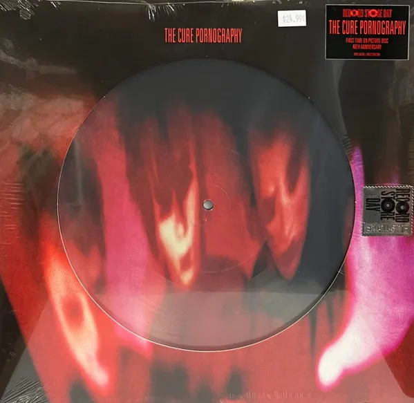 A shrink-wrapped picture disc vinyl whose surface bears a blurred, heavily distorted red and magenta image of three ghostly faces against black, with matching smeared imagery extending onto the sleeve.