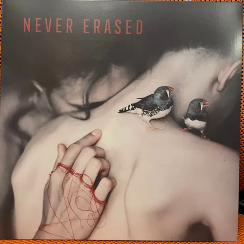 A muted, desaturated photograph of two bare-skinned figures embracing, with two zebra finches perched on a shoulder and a hand tangled in scribbled red thread, under thin red capital lettering at the top.